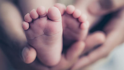 Feet of a newborn baby in the hands of parents.