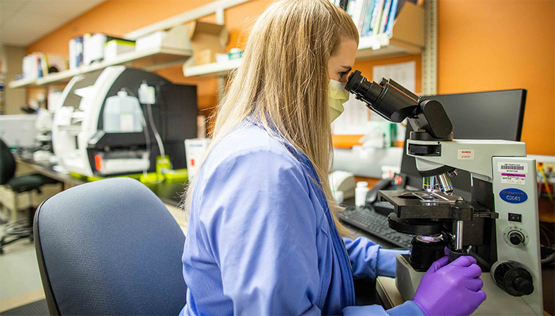 WMC Laboratory staff looks through microscope.