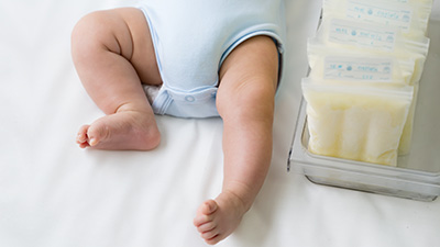 Leg of newborn baby and breast milk frozen in storage plastic bag, Breastfeeding from pumping milk mother