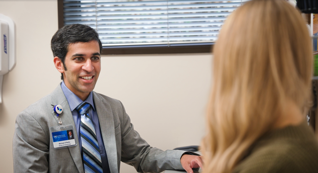 Dr. D'Netto discussing allergy care with a patient