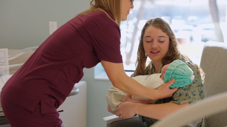 Nurse handing baby to mom