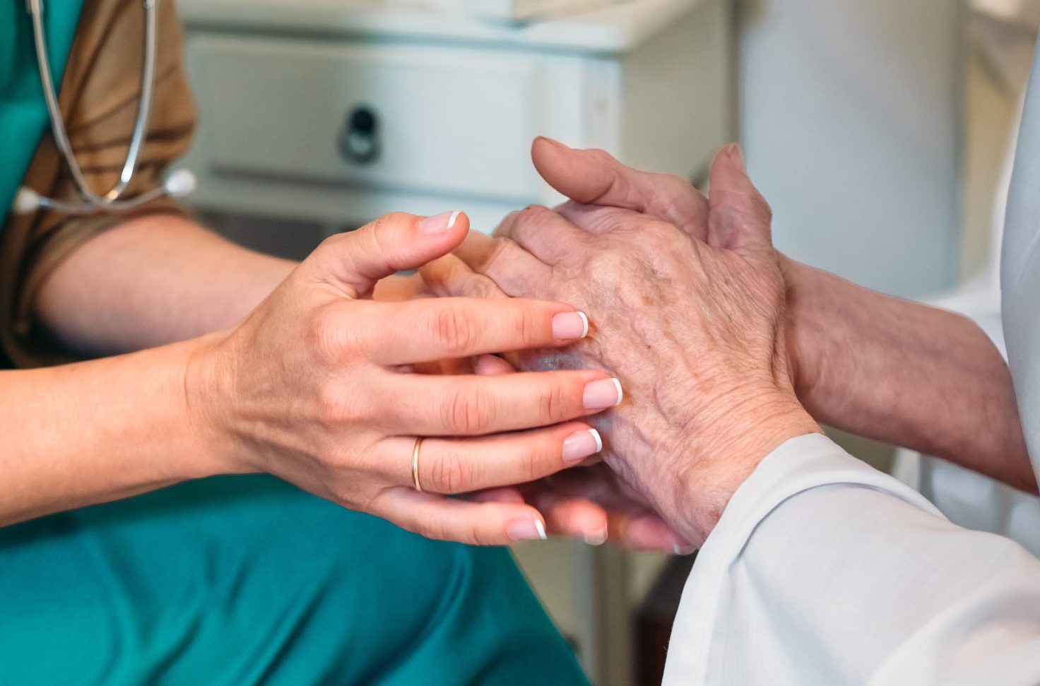 Giving encouragement to elderly patient by holding her hands
